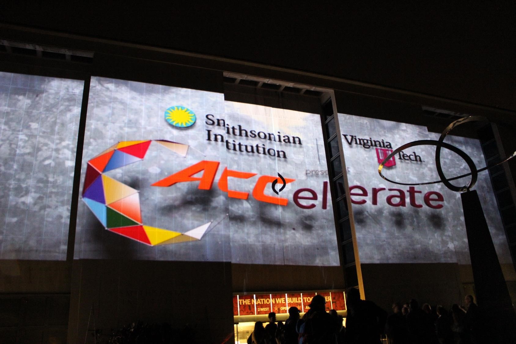 A projection of the ACCelerate logo is displayed on the exterior of the Smithsonian National Museum of American History.